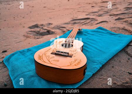 Scatto ad angolo alto di una chitarra su una coperta blu sulla sabbia Foto Stock