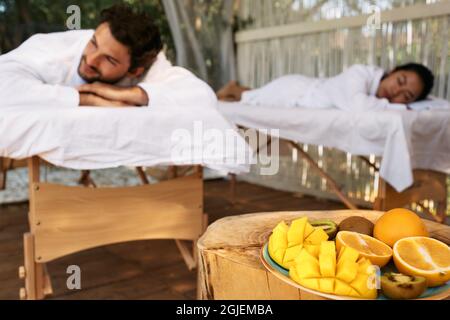 Coppia sdraiata sui tavoli da massaggio mentre si svolge il day-spa e un romantico weekend con frutta esotica presso il resort spa. massaggio per coppia Foto Stock