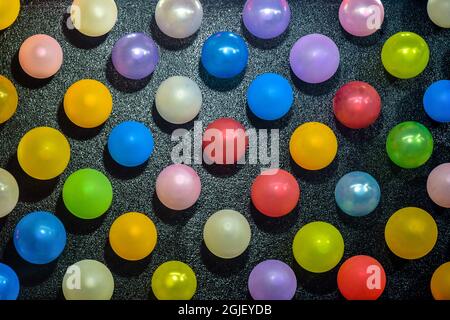 File di un gran numero di palloncini colorati su uno sfondo nero, bella ripetizione. Primo piano. Messa a fuoco selettiva. Foto Stock