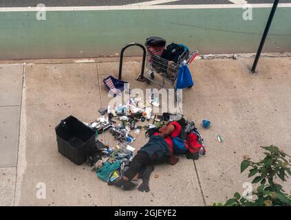 L'individuo senza tetto dorme nel mezzo del marciapiede a Chelsea a New York con i suoi possedimenti sparsi circa, visto la domenica 29 agosto 2021. (© Richard B. Levine) Foto Stock