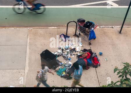 L'individuo senza tetto dorme nel mezzo del marciapiede a Chelsea a New York con i suoi possedimenti sparsi circa, visto la domenica 29 agosto 2021. (© Richard B. Levine) Foto Stock