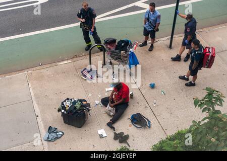 I membri del FDNY aspettano come un individuo senza tetto raccoglie i suoi possedimenti dopo aver dormito nel mezzo del marciapiede a Chelsea a New York domenica 29 agosto 2021. (© Richard B. Levine) Foto Stock