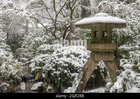 Portland, Oregon. Lanterna di pietra arpa coperta di neve e ponte lunare, Giardino giapponese di Portland. Foto Stock