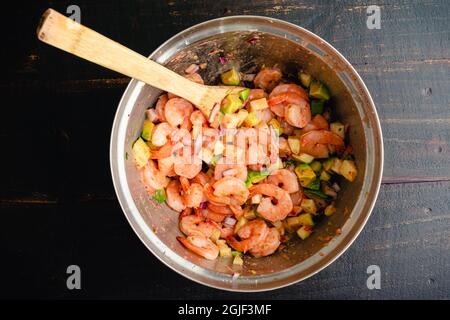 Gamberetti Ceviche cocktail ingredienti in un recipiente di miscelazione: Gamberetti, avocado, e altri ingredienti mescolati con vinaigrette condimento Foto Stock