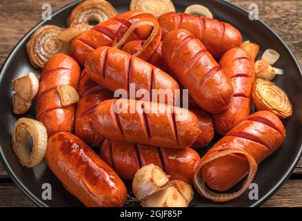 Le salsicce fritte si avvicinano in una vista laterale sul piatto nero. Foto Stock