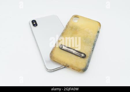 Nuovo smartphone e custodia in silicone vecchia e sporca a causa di macchie e muffe gialle. Isolato su sfondo bianco. Foto Stock