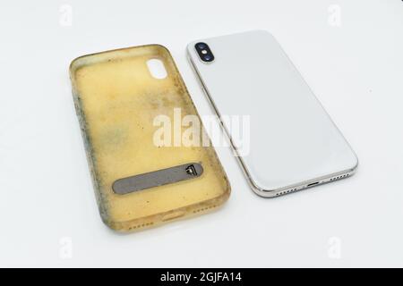 Nuovo smartphone e custodia in silicone vecchia e sporca a causa di macchie e muffe gialle. Isolato su sfondo bianco. Vista laterale. Foto Stock