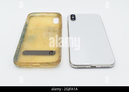 Nuovo smartphone e custodia in silicone vecchia e sporca a causa di macchie e muffe gialle. Isolato su sfondo bianco. Vista frontale. Foto Stock