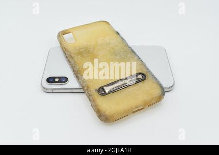 Nuovo smartphone e custodia in silicone vecchia e sporca a causa di macchie e muffe gialle. Isolato su sfondo bianco. Foto Stock