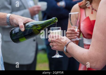 L'uomo versa lo champagne in un bicchiere di vino di una donna vestita di rosso. Foto di alta qualità Foto Stock