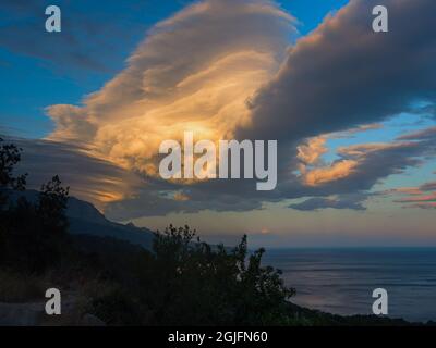Una nube di tuorlo nella luce del tramonto arancione-beige. Cielo drammatico e tempestoso. Un'enorme nube di cumulo sotto forma di idromassaggio. Un portatore di maltempo, cli Foto Stock