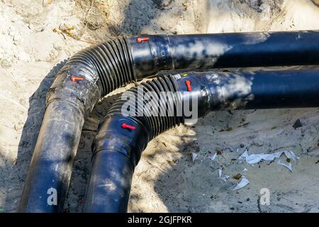 rotazione ad angolo retto del nuovo tubo di riscaldamento isolato termicamente in una trincea scavata Foto Stock