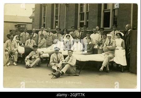 Cartolina fotografica originale dell'era della prima Guerra Mondiale di soldati feriti con infermieri, (molti di loro membri dei distaccamenti volontari locali di aiuto o VAD) fuori Davidson Rd. War Hospital, South Norwood, Londra, Regno Unito anche i letti di reparto sono stati portati fuori. L'ospedale era in funzione dal 1915 al 1919. Foto Stock