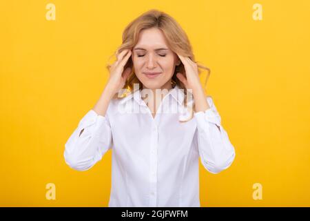 Donna infelice regista soffre di emicrania attacco sfondo giallo, mal di testa Foto Stock