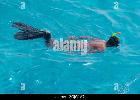 Un turista maschio nuota in una maschera e pinne sul mare Foto Stock