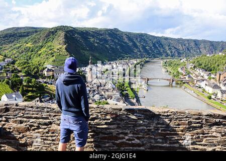 Un giovane uomo che si affaccia sulla città di Cochem dal castello imperiale. Foto Stock