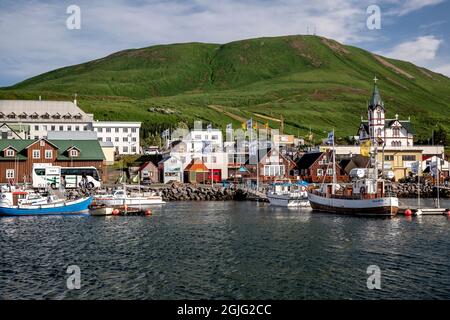 Barche, gli edifici colorati e chiesa, Husavik Harbour, Husavik, Islanda Foto Stock