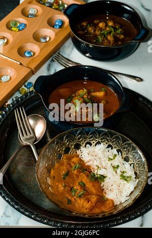 Giocare gioco da tavolo mancala mentre si mangia cibo indiano tra cui pollo tikka e pindi chana masala così come aloo matar Foto Stock