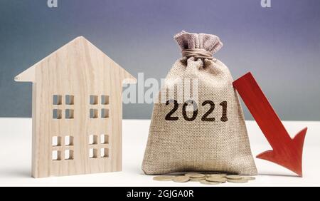 Casa di legno e borsa di 2021 soldi con freccia giù. Previsione del concetto di mercato immobiliare. Tassi di interesse in calo. Investimenti, utili e redditi. De Foto Stock