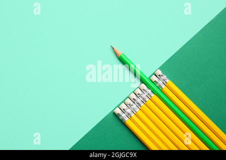 Matita verde tra quelle gialle su sfondo colorato. Concetto di unicità Foto Stock