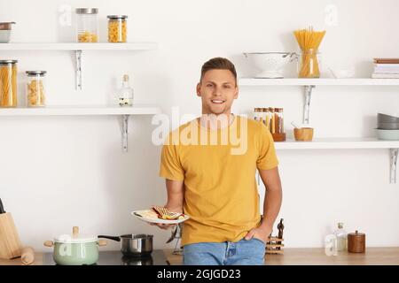 Bel giovane uomo che mangia gustosa quesadilla a casa Foto Stock