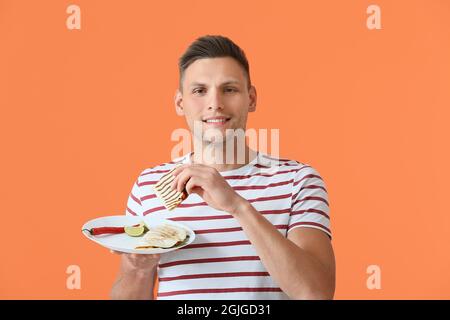 Giovane uomo che mangia gustosa quesadilla su sfondo colorato Foto Stock