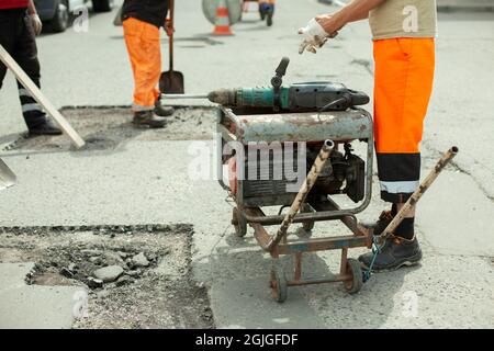 Generatore di benzina di elettricità. Alimentazione all'utensile elettrico. Generatore sulla strada per la riparazione stradale. Foto Stock