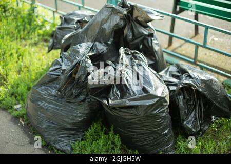 Sacchetti di spazzatura sulla strada. Sacchetti di plastica neri per la raccolta dei rifiuti in città. Il risultato della pulizia nei sacchi da cortile con immondizia. Foto Stock