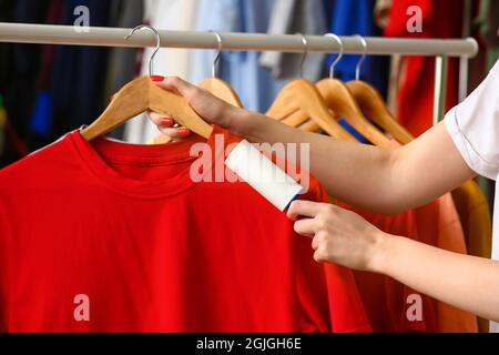 Donna che pulisce la t-shirt con il rullo di pelucchi in camera Foto Stock