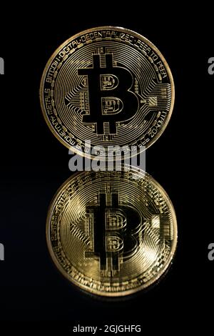 Bitcoin d'oro sulla parte superiore di uno specchio e sfondo nero Foto Stock