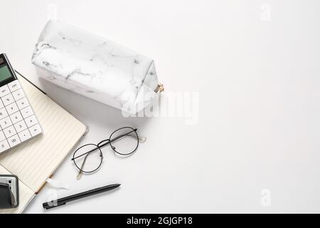 Custodia a matita, occhiali e cancelleria su sfondo bianco, primo piano Foto Stock