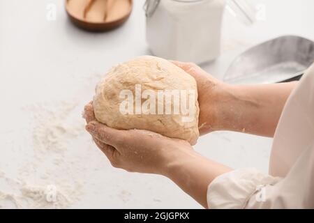 Chef femminile che prepara l'impasto sul tavolo da cucina, guardaroba Foto Stock