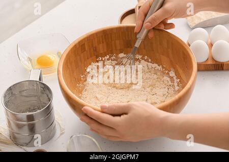 Chef femminile che prepara l'impasto sul tavolo da cucina, guardaroba Foto Stock