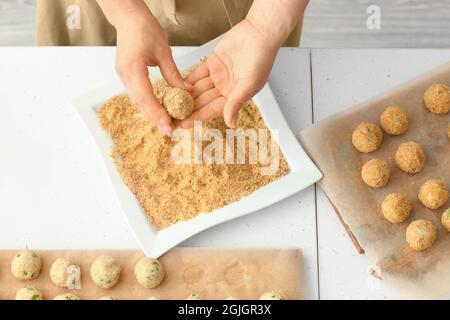 Donna che cucinano le cotolette di merluzzo a tavola Foto Stock