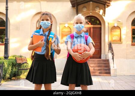 Ragazze scolastiche carine in maschere mediche all'aperto Foto Stock