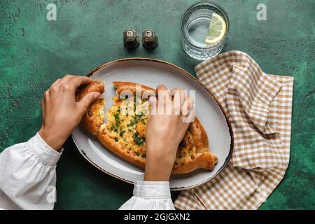 Donna che mangia gustoso khachapuri Ajarian su sfondo colorato Foto Stock