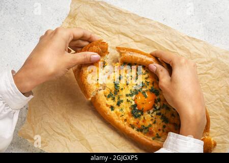 Donna che mangia gustoso khachapuri Ajarian su sfondo chiaro Foto Stock