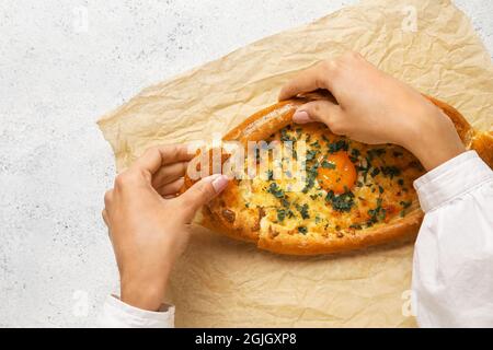 Donna che mangia gustoso khachapuri Ajarian su sfondo chiaro Foto Stock