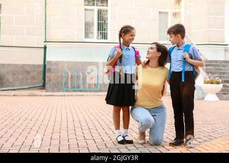 Madre che dice Arrivederci ai suoi piccoli figli vicino a scuola Foto Stock