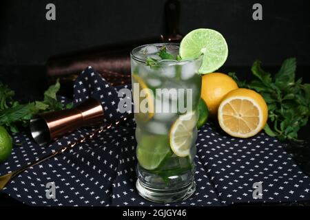 Bicchiere di mojito fresco, limoni e menta su sfondo scuro Foto Stock