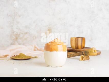 Bicchiere di gustosa dalgona hojicha latte su sfondo chiaro Foto Stock