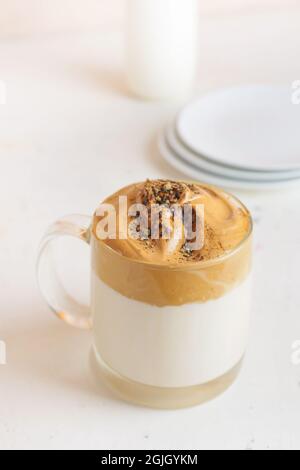 Bicchiere di gustoso latte di dalgona hojicha su sfondo chiaro Foto Stock