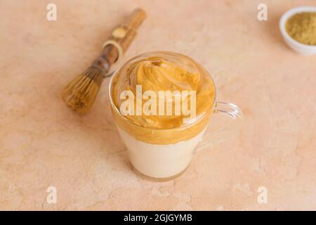 Bicchiere di gustosa dalgona hojicha latte su sfondo colorato Foto Stock