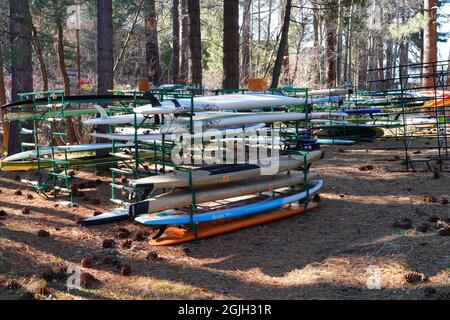 INCLINE VILLAGE, NV –11 Apr 2021- Racks di kayak colorati e tavole da surf nei boschi sulla riva del lago Tahoe. Foto Stock