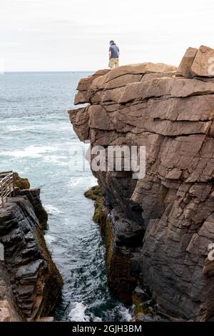 Acadia National Park, Maine, USA. Uomo in piedi sulla scogliera accanto a Thunder Hole. Foto Stock