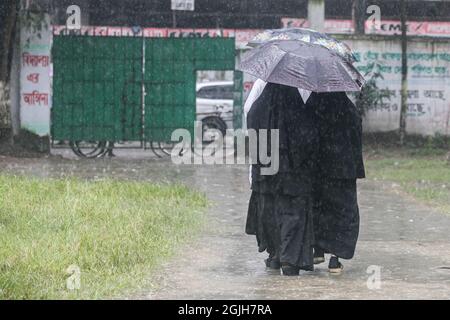 Dhaka, Bangladesh. 9 settembre 2021. La gente si ripara dalla pioggia sotto gli ombrelloni durante una pioggia su Dhaka Street.monsoon downpour ha causato il disboscamento dell'acqua nella maggior parte delle zone della città di Dhaka, Bangladesh. Le strade sono state sommerse rendendo il viaggio lento e pericoloso. Il monsone downpour ha causato il disboscamento dell'acqua nella maggior parte delle zone della città di Dhaka, le strade sono state sommerse rendendo il viaggio lento e pericoloso. (Foto di Sazzad Hossain/SOPA Images/Sipa USA) Credit: Sipa USA/Alamy Live News Foto Stock