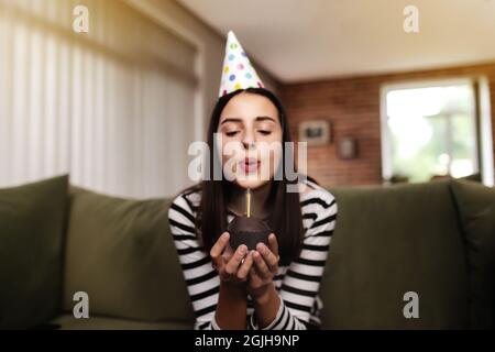 La ragazza di compleanno soffia fuori una candela che brucia su un cupcake Foto Stock