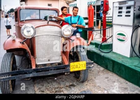 I cubani che riempiono una vecchia auto classica americana a benzina, Sancti Spiritus, Cuba Foto Stock