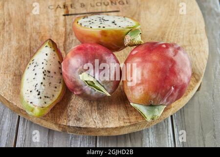 Frutta di cactus di mela peruviana intera e tagliata su supporto di legno su tavola grigia. Nome scientifico Cereus repandus. Foto Stock