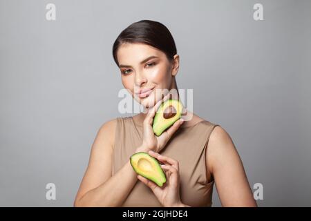 Felice bella moda modella donna che tiene avocado e sorridente Foto Stock